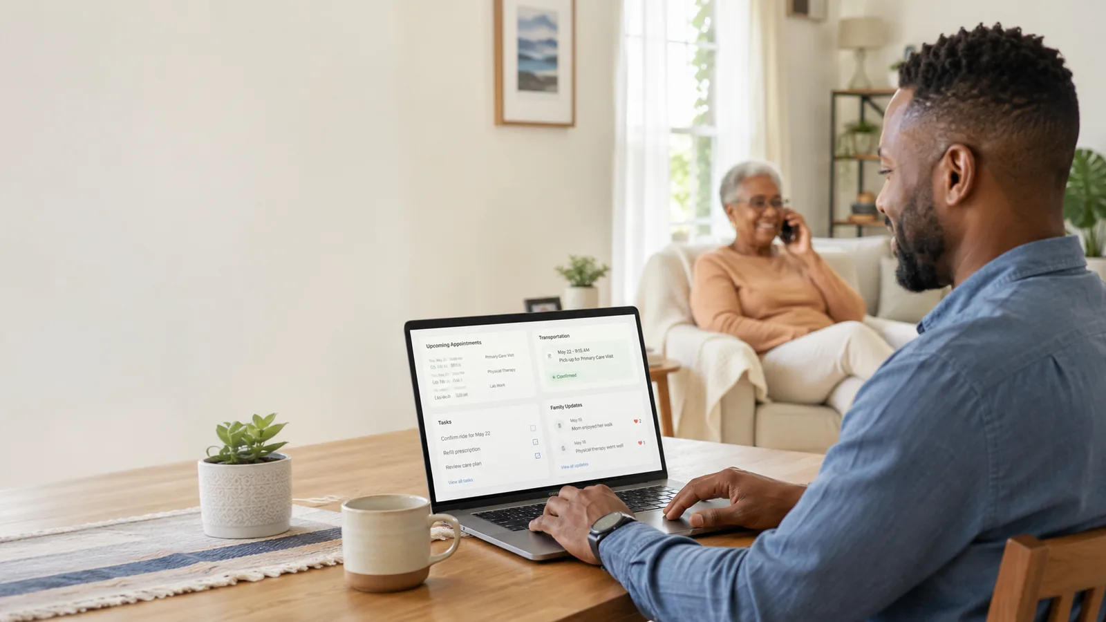 A man reviews his mother's upcoming appointments and transportation on a laptop while she takes a phone call nearby.